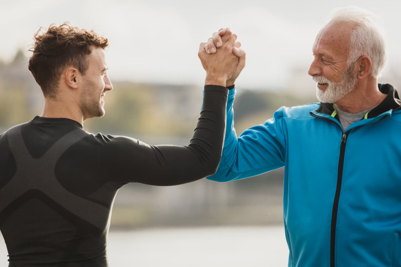 A young man and an older man high-five outdoors