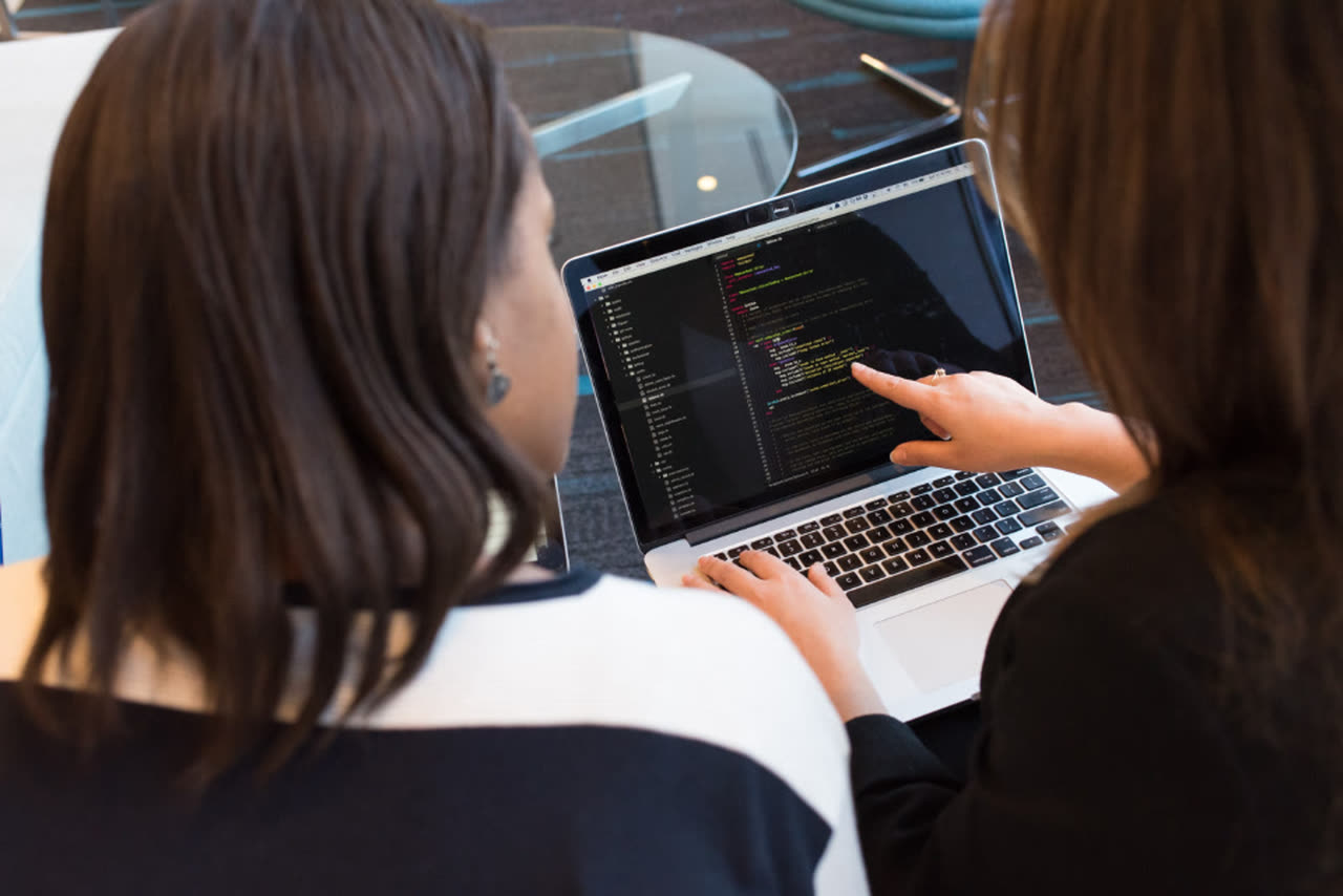 Two developers reviewing code on a laptop
